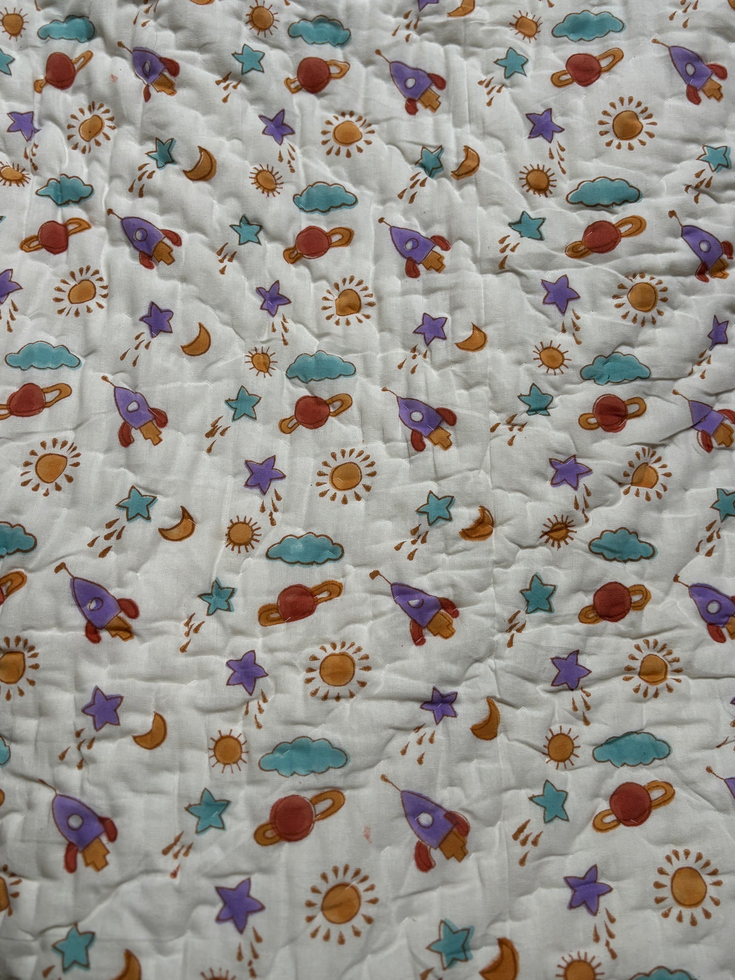 Baby boy’s cotton Quilt with space-themed pattern featuring stars, planets, and rockets on a white background.