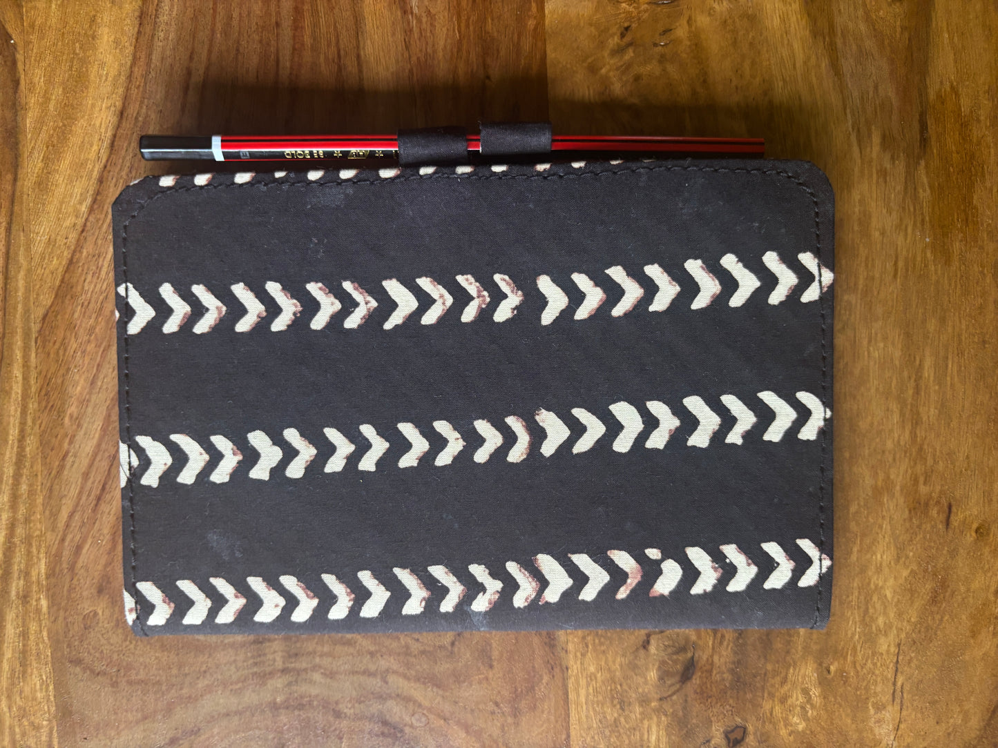 Black diary with white arrow pattern on a wooden surface