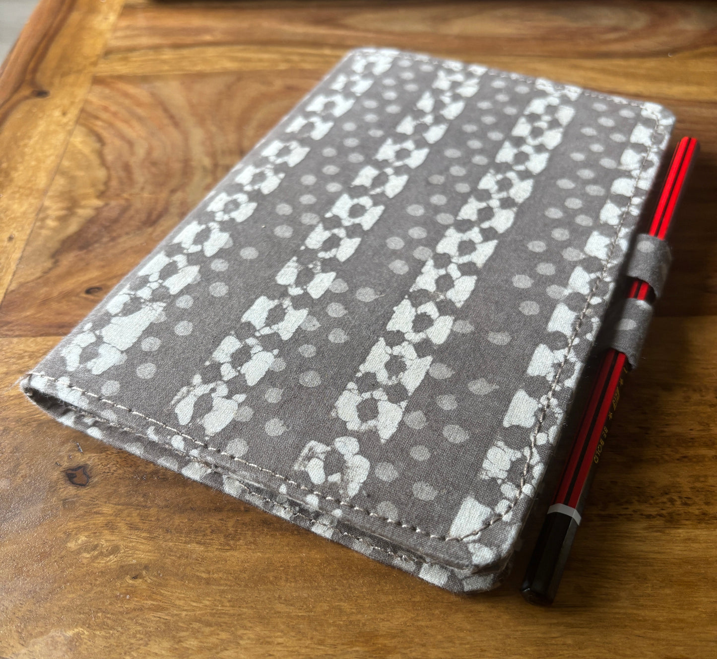 Gray patterned journal with a pen on a wooden surface