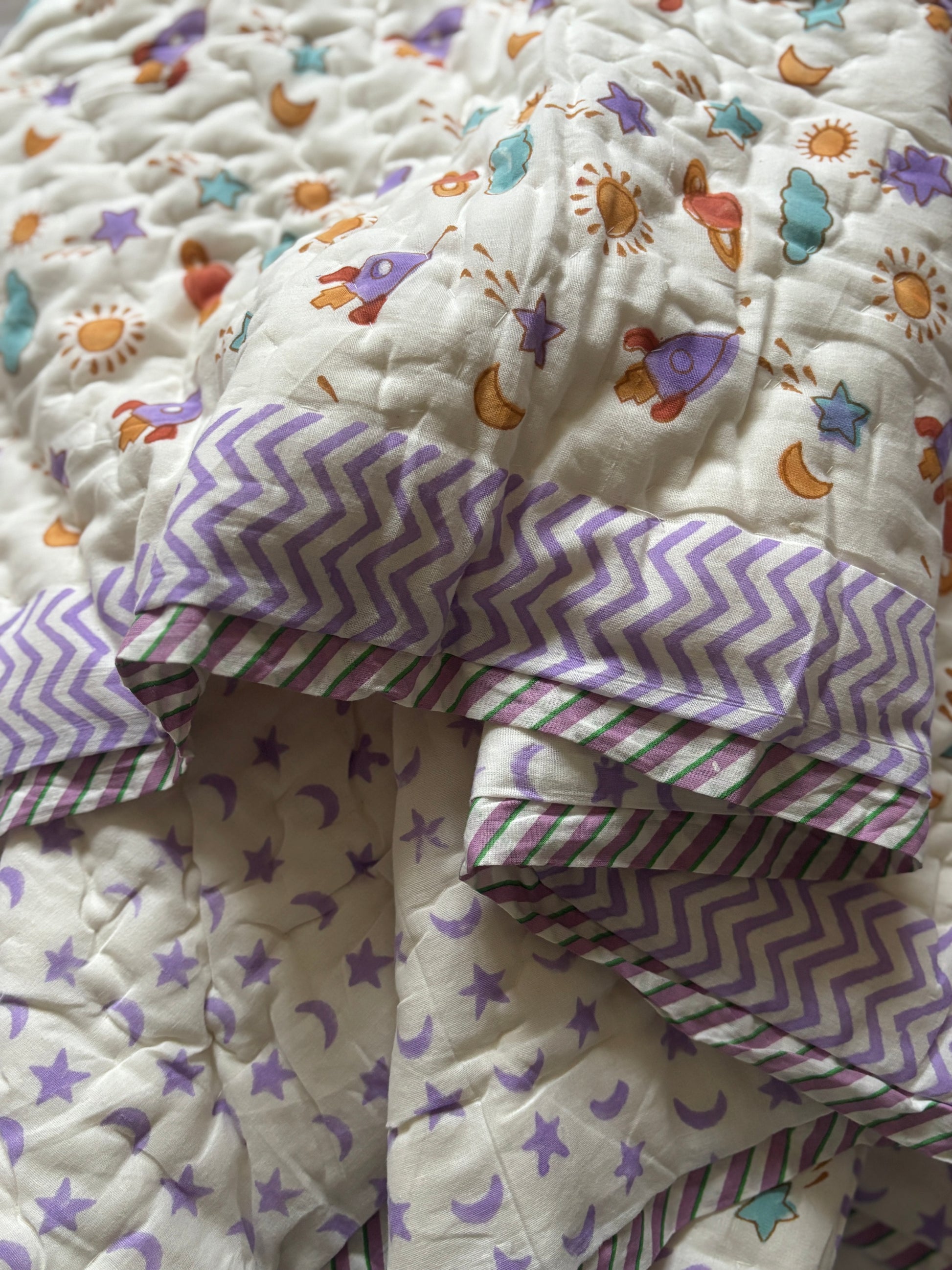 Moon Rocket Dream baby quilt in soft pastel colors, lightweight and breathable cotton bedding for infants.