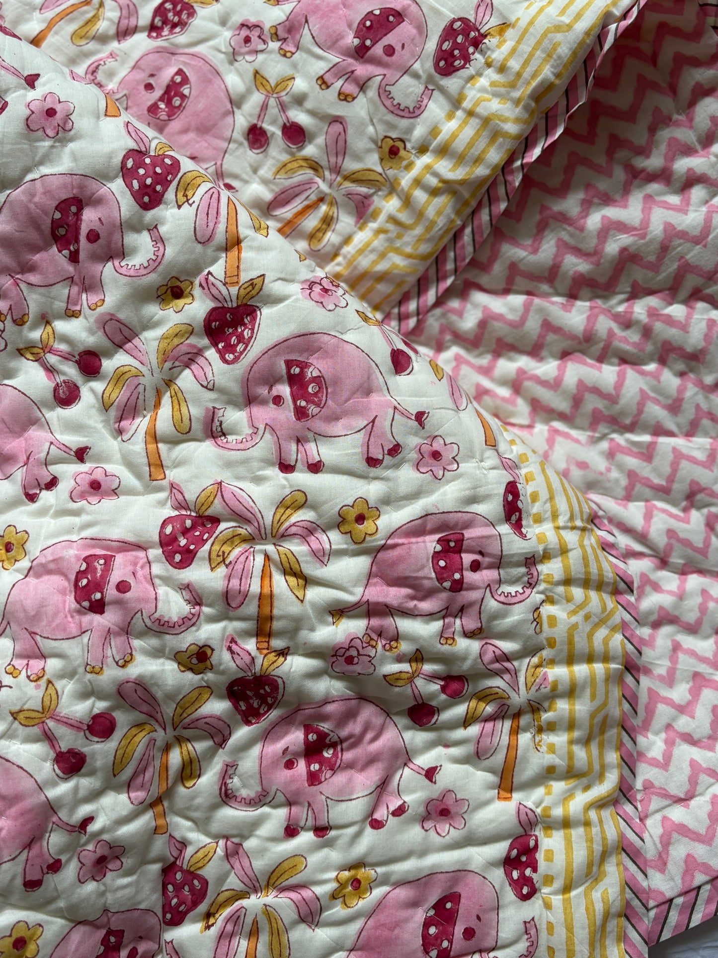Quilt with pink elephant pattern on a white background