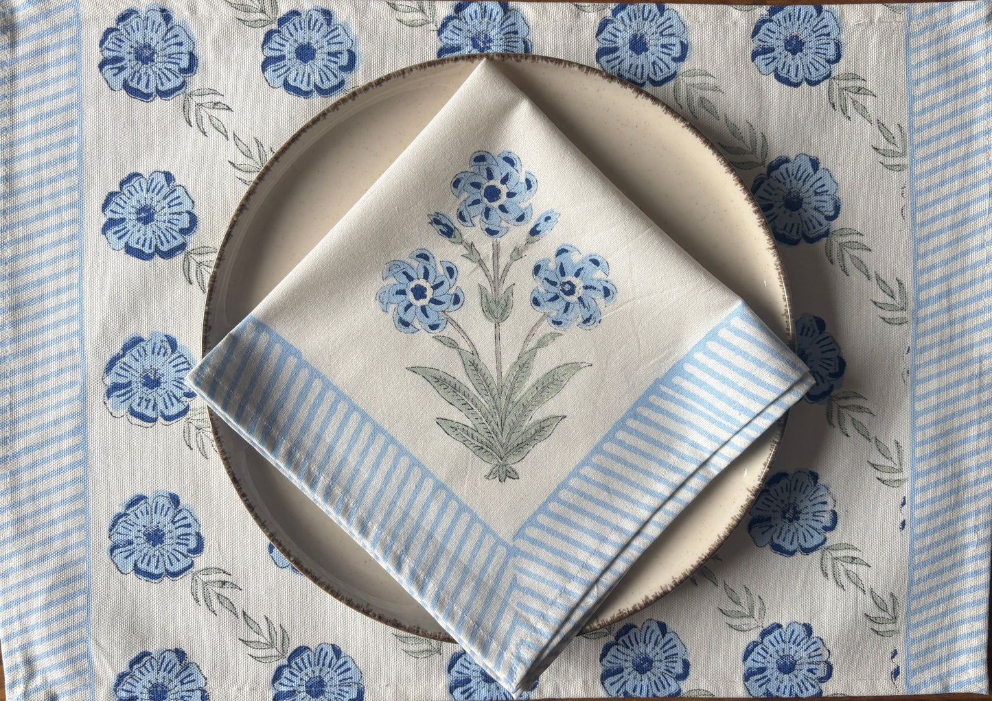 Placemat with blue floral pattern, plate, and folded napkin 