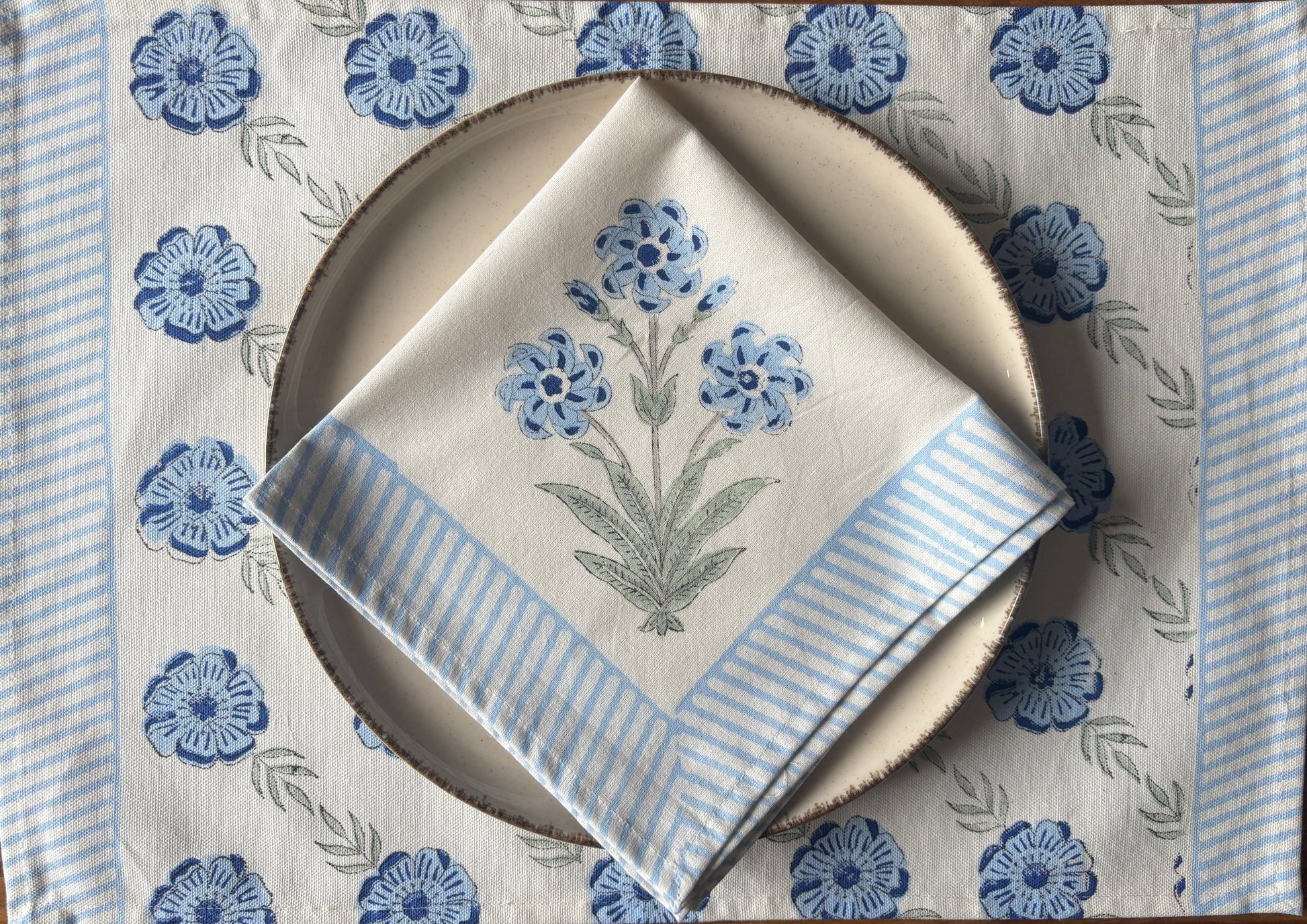 Placemat with blue floral pattern, plate, and folded napkin 