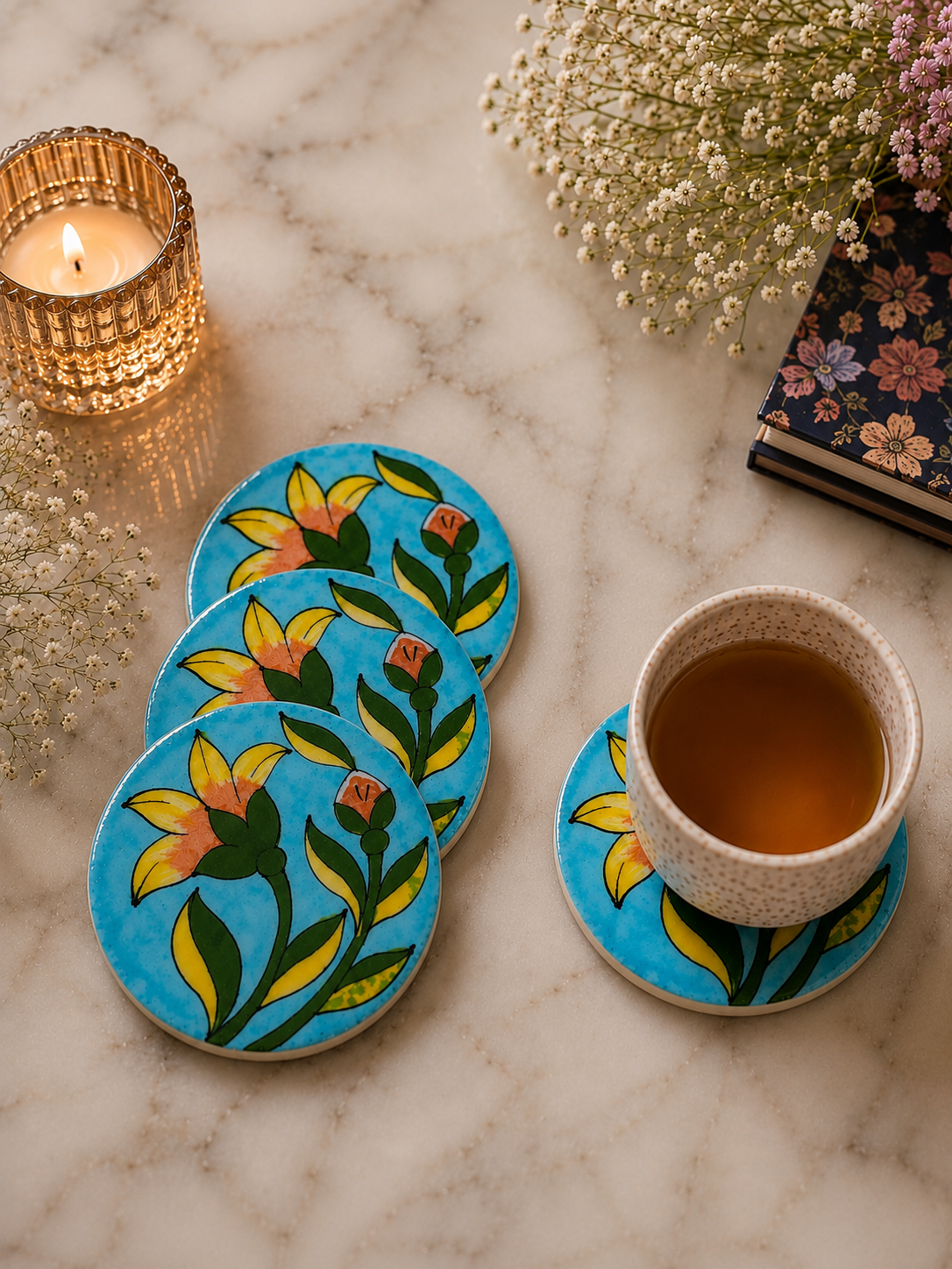 Floral coasters on a marble surface with a cup of tea and decorative elements.