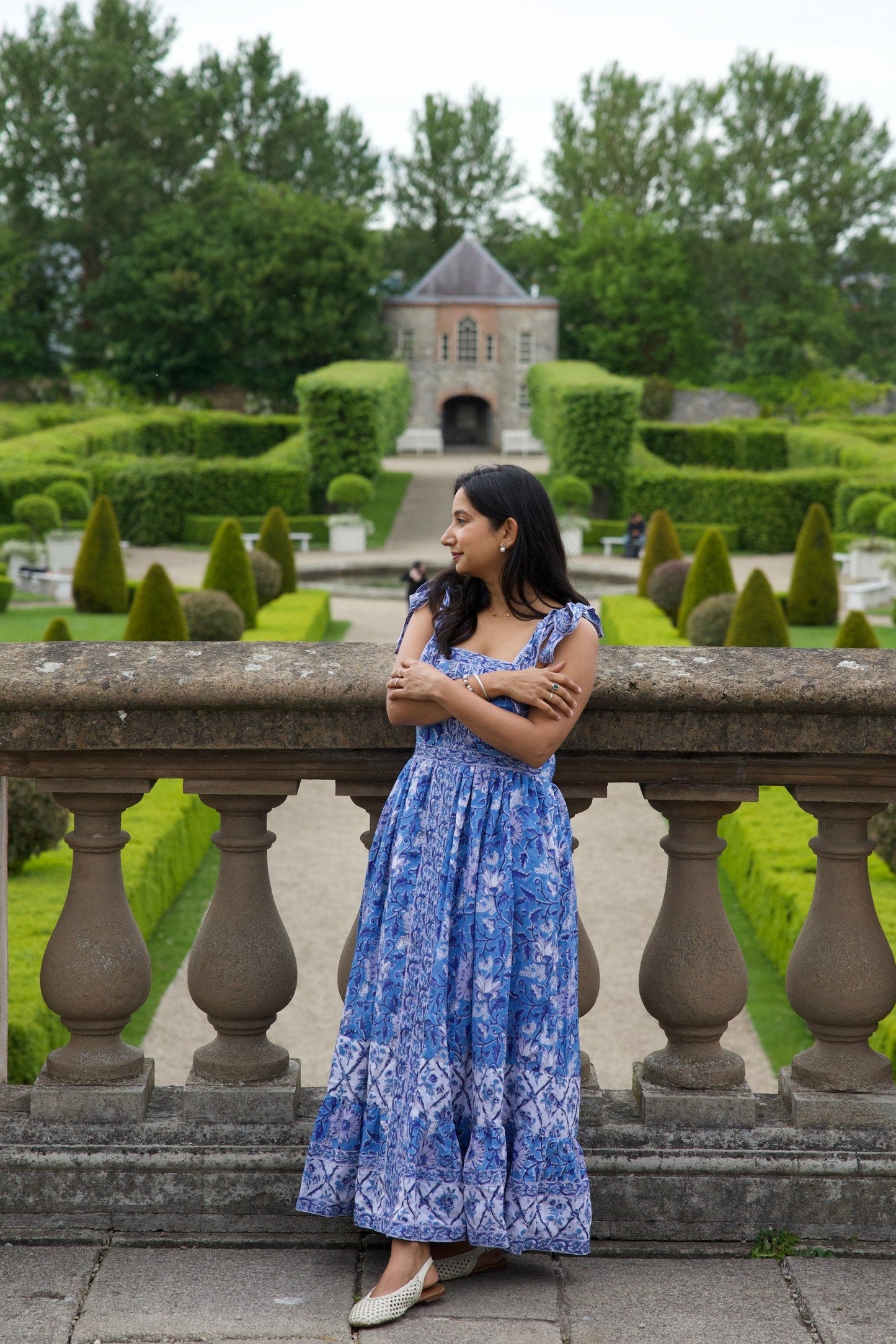 Woman in a blue block printed cotton maxi dress standing in an Irish  garden