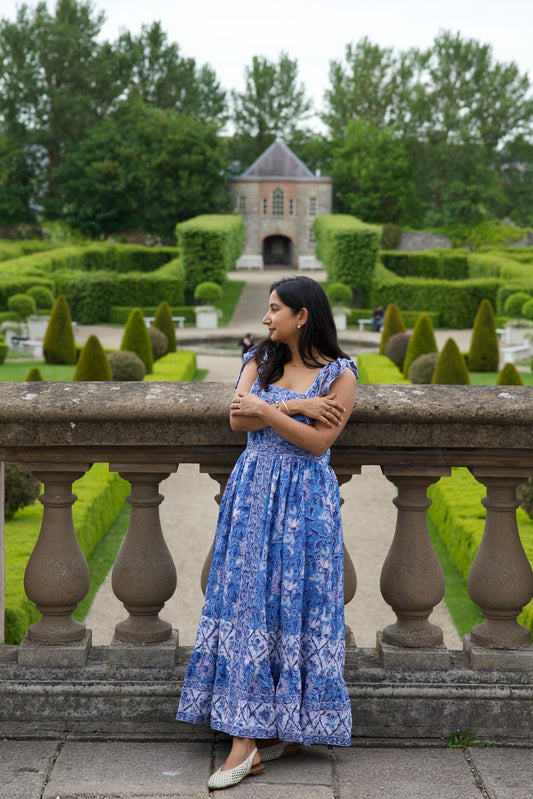 Woman in a blue block printed cotton maxi dress standing in an Irish  garden