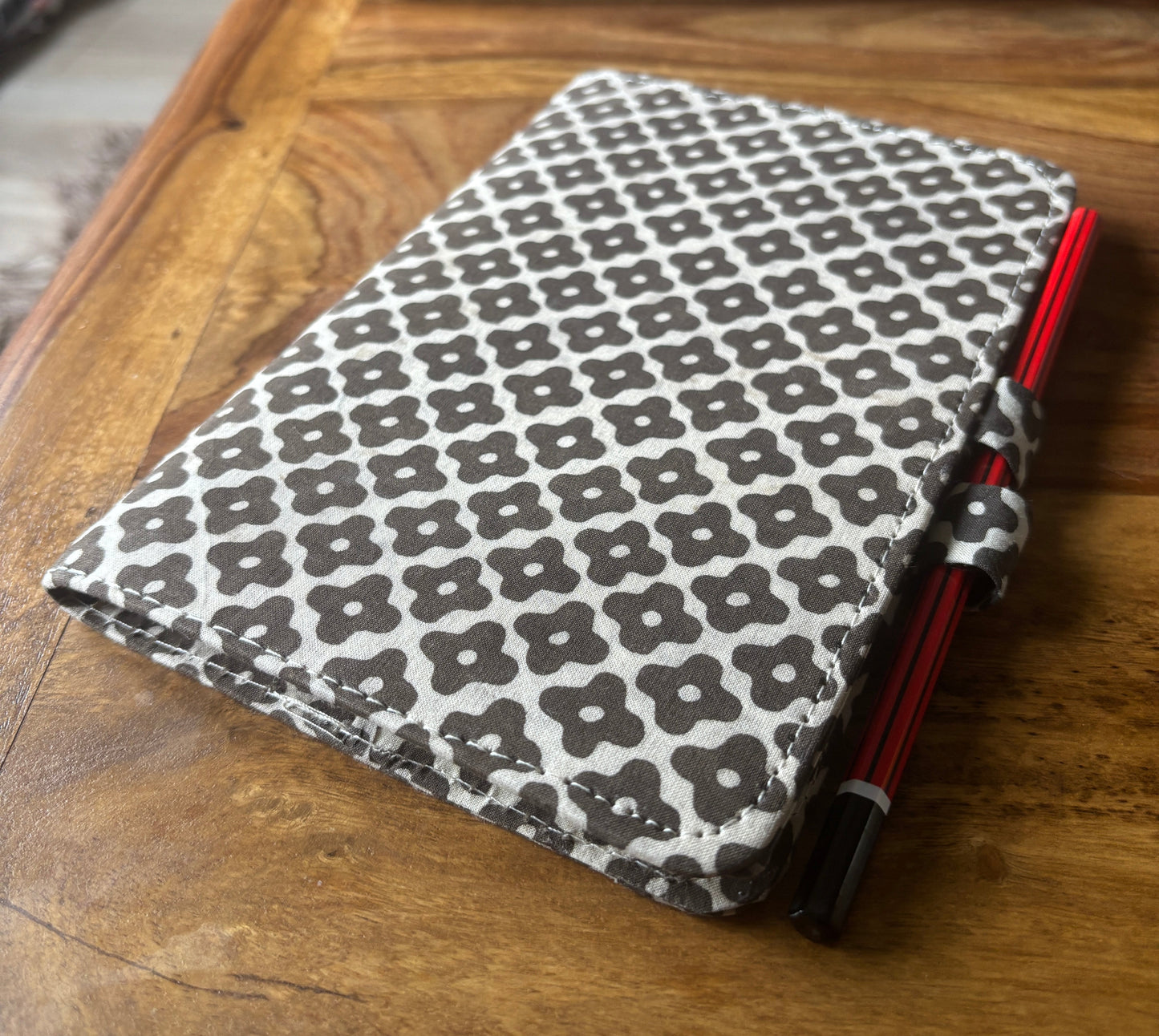 Black and white patterned journal with pencil attached on a wooden surface