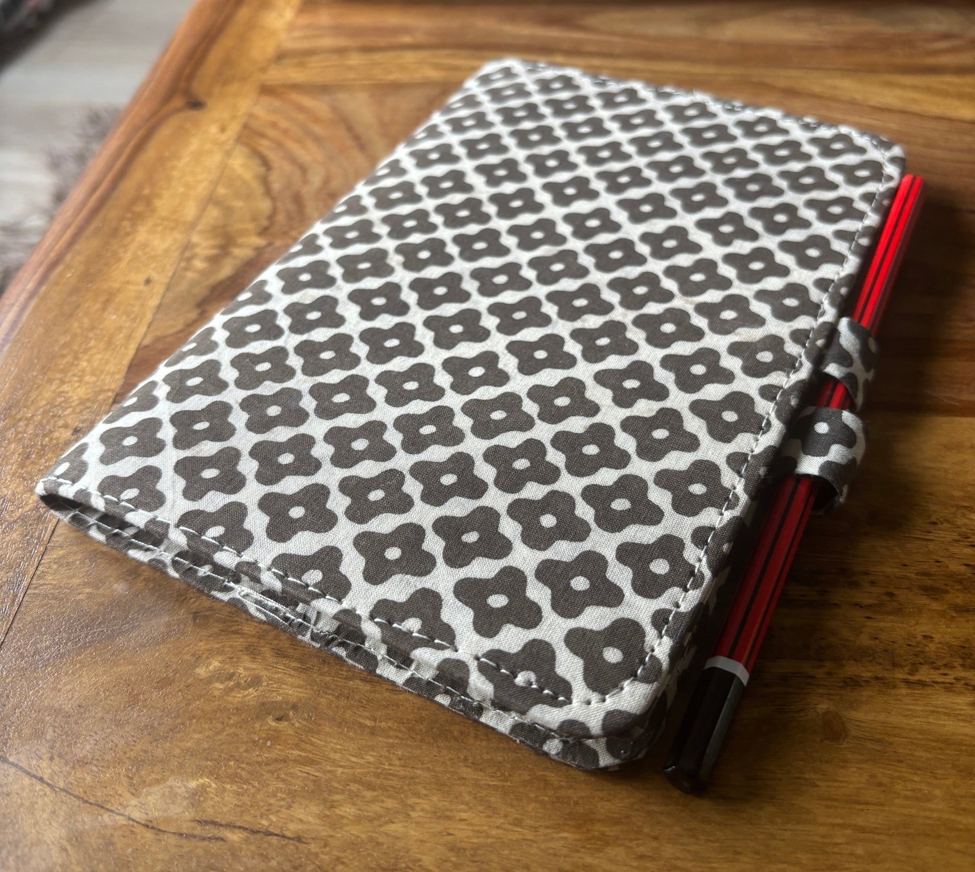 Black and white patterned journal with pencil attached on a wooden surface