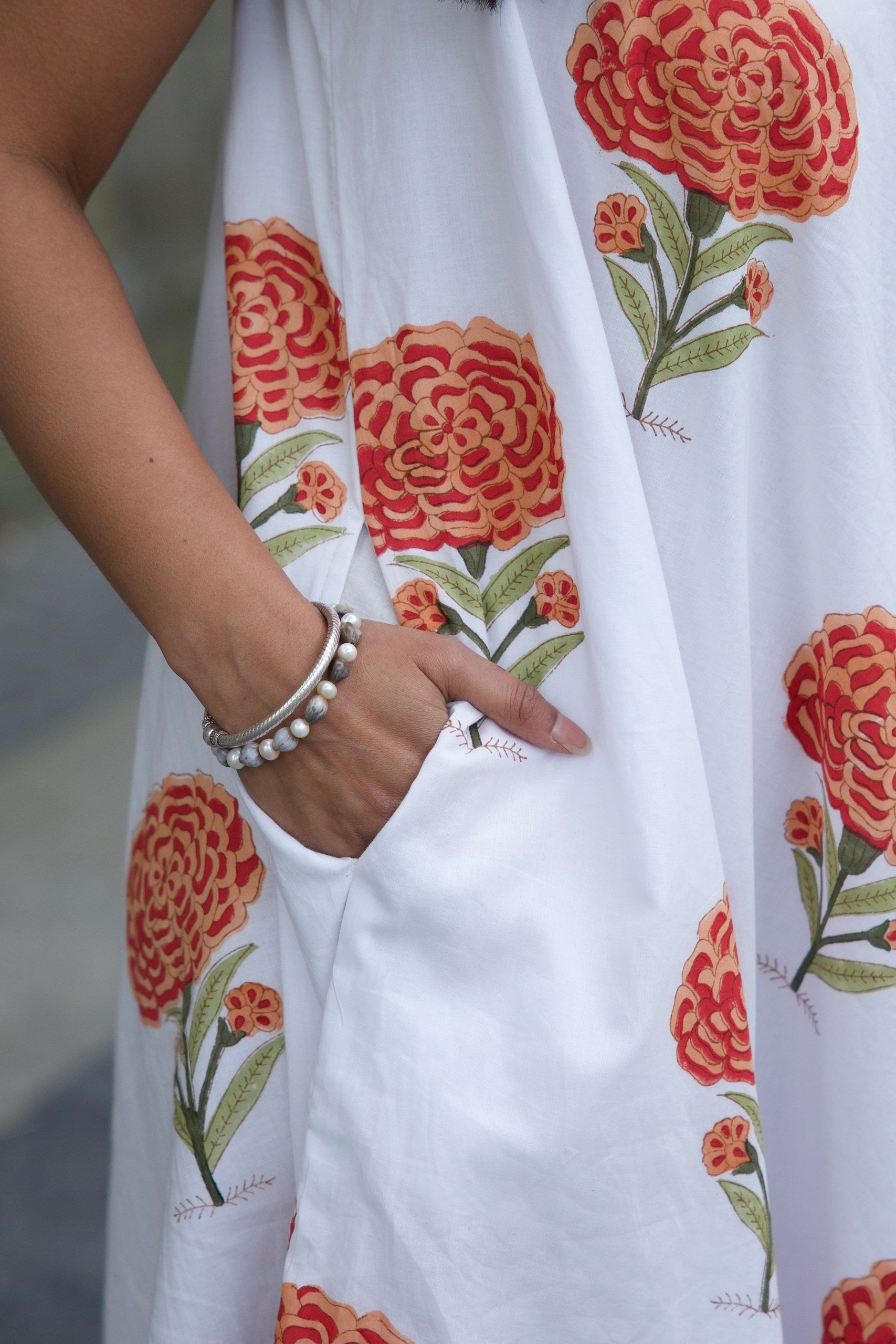 white cotton dress with large orange floral patterns and pockets