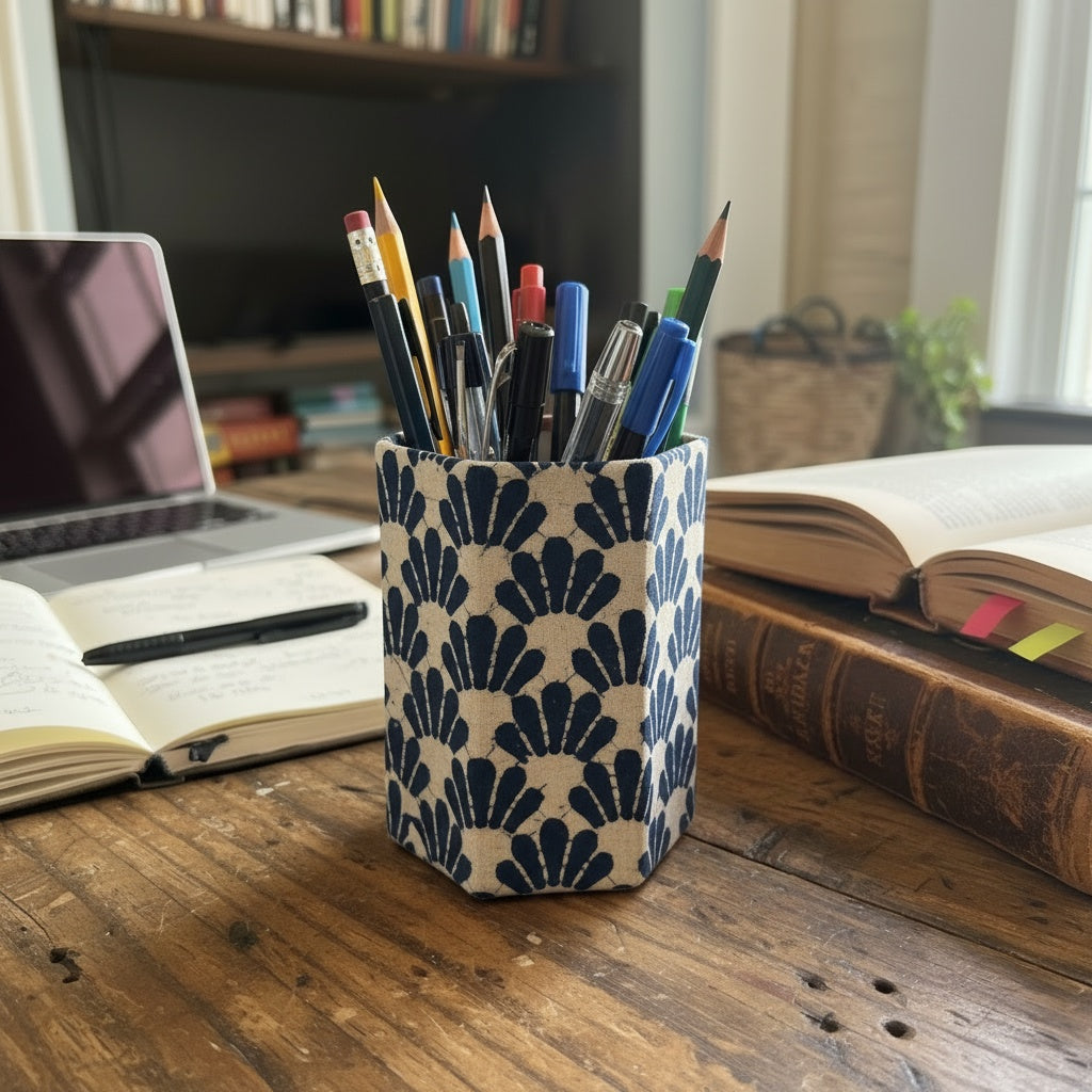 Pen holder with pens and pencils on a desk with books and a laptop in the background